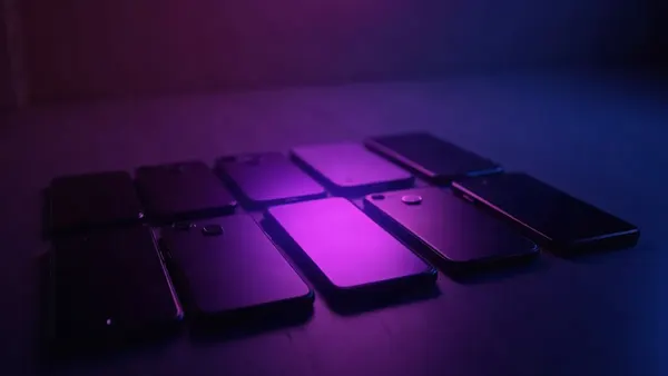 Několik smartphonů v řadě, fialový reflektor míří na ten prostřední (ilustrace k článku)